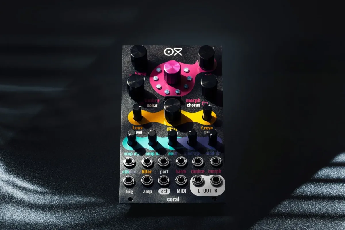 Black-panel OXI Coral Eurorack module, with knobs set on pink, yellow and teal shapes and two rows of jacks, on a dark background
